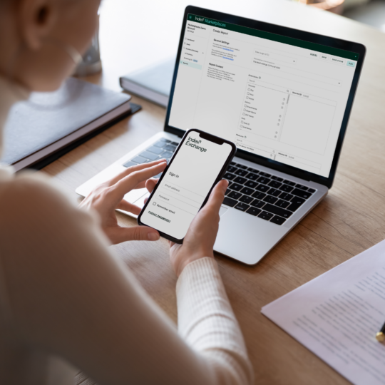 Index Exchange UI displayed on a cell phone and laptop screen with a person sitting in front of each at a desk.